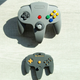 An image of a BabyGlitch toy N64 controller beneath a much larger real N64 controller.